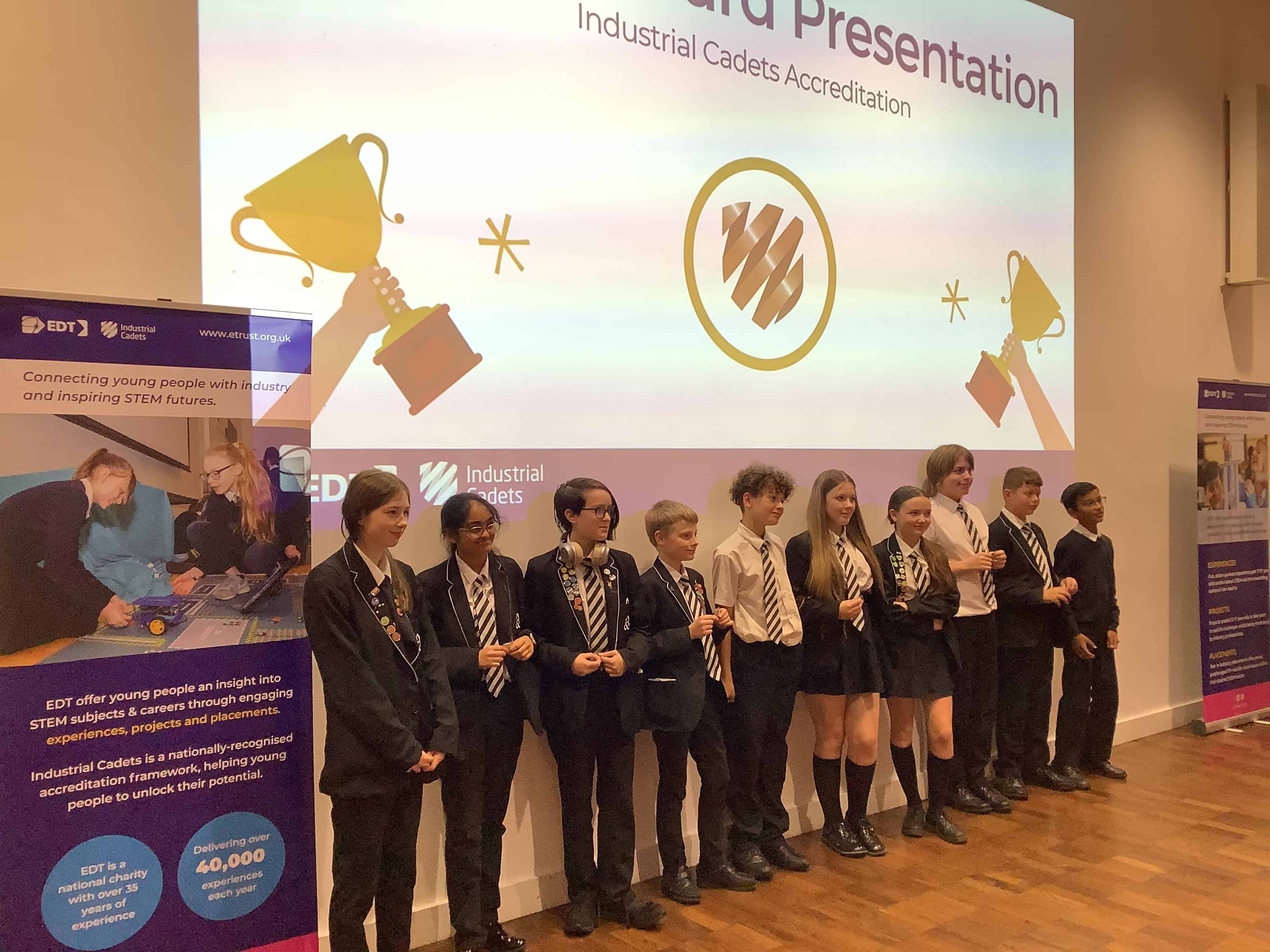 10 of the 12 students representing Laurus Ryecroft at the Industrial Cadet Awards at Sheffield Hallam University stand at the front of the hall smiling.