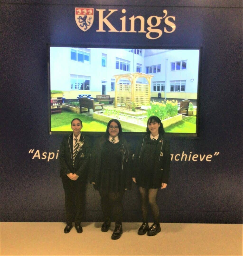 The girls stand in front of a King's sign
