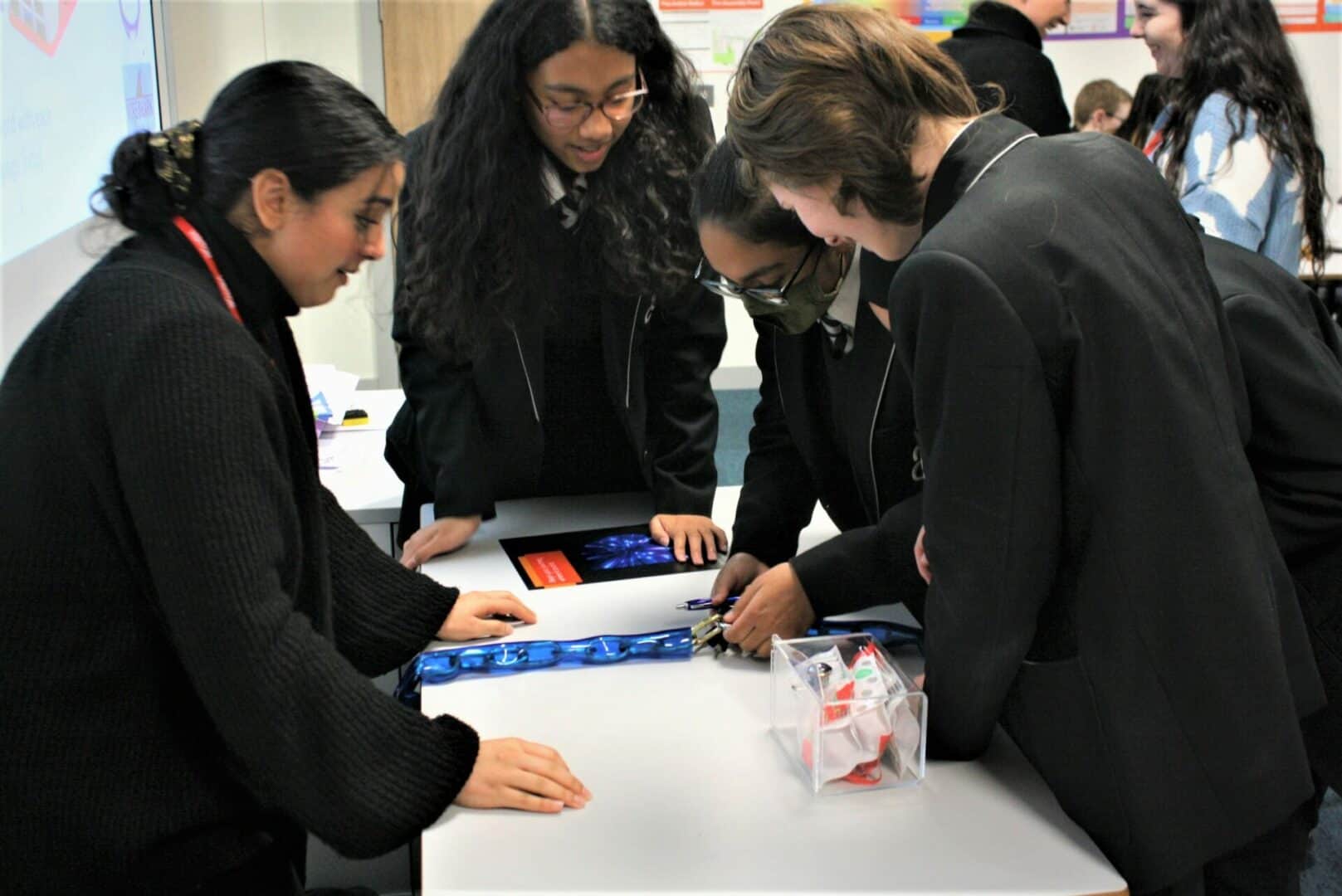 students gather around a table, working together on a task as part of the workshop