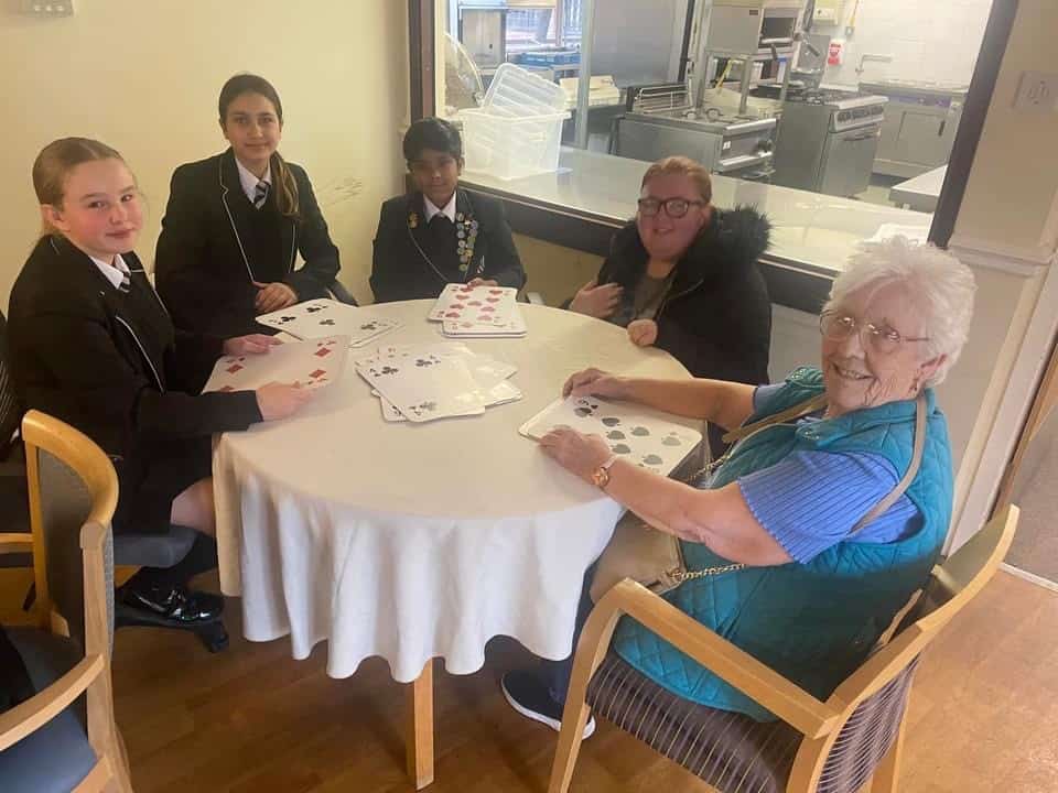 Laurus Ryecroft students sit with residents playing board games at a local care home.
