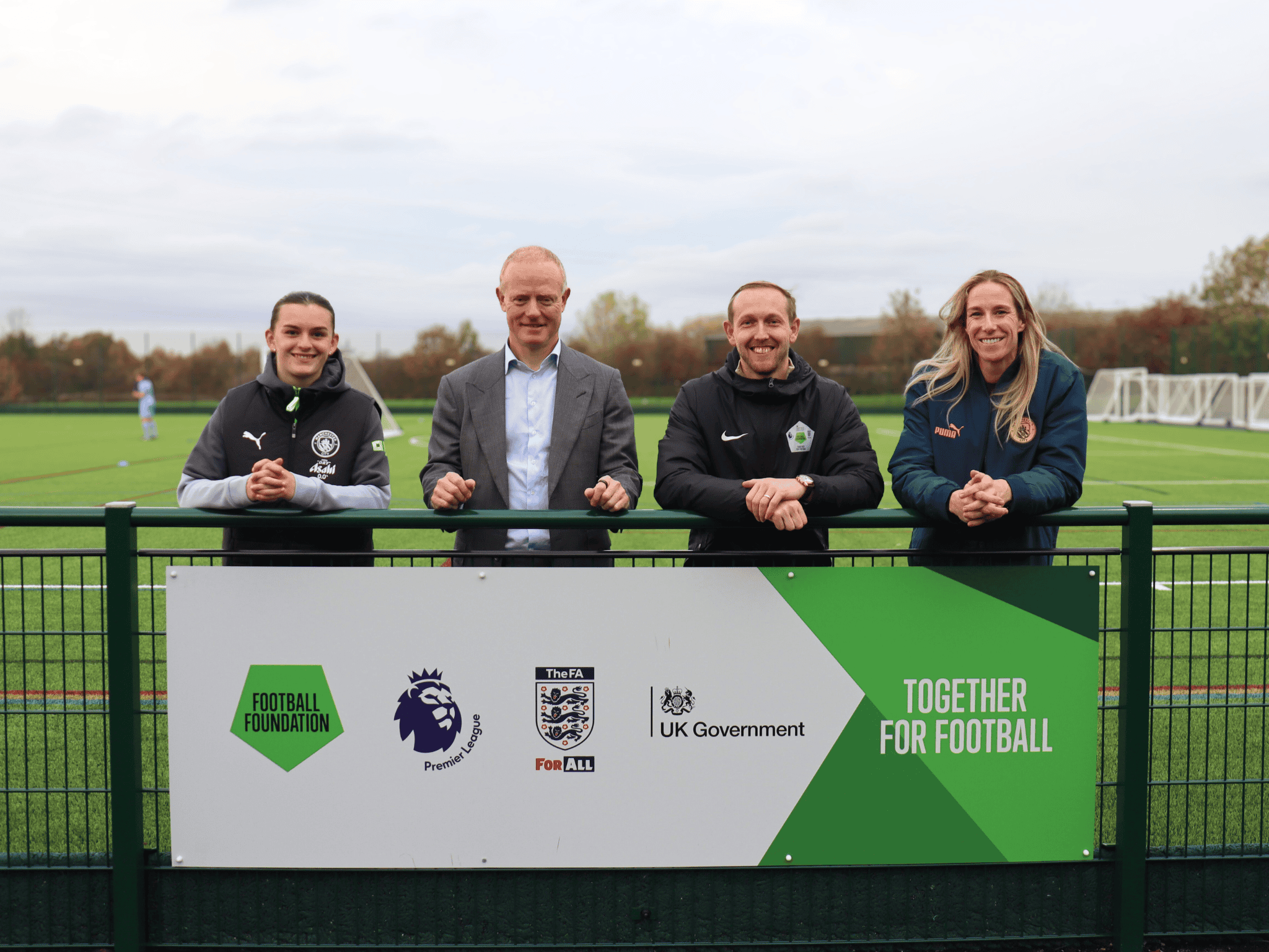 Shot with sign - Laurus Ryecroft Lily Murphy, Andrew Law, Liam Devlin and Karen Bardsley stand on the new 3g pitch at Laurus Ryecroft, behind a sign for the Football Foundation